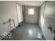 Unfinished basement with white painted walls and floors, showcasing a door and window at 3026 S Rybolt Ave, Indianapolis, IN 46241