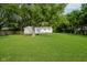 Large backyard featuring a spacious lawn, mature trees, and a white house in the background at 3538 N Elizabeth St, Indianapolis, IN 46226