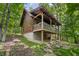 Log cabin with a red roof and covered porch, nestled in a lush, green forest at 3715 Orchard Rd, Columbus, IN 47201