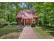 Charming log cabin with a red metal roof, wooden walkway, and surrounded by lush greenery at 3715 Orchard Rd, Columbus, IN 47201