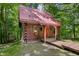 Quaint log cabin with a red metal roof and a small porch entrance in a wooded setting at 3715 Orchard Rd, Columbus, IN 47201