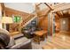 Cozy living room featuring wood-paneled walls, a leather sofa, and a charming wooden staircase at 3715 Orchard Rd, Columbus, IN 47201