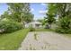 Spacious backyard featuring a grassy lawn, gravel area, mature trees, and a charming house at 4129 Cornelius Ave, Indianapolis, IN 46208