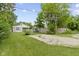 A lovely backyard with lush grass, trees, a gravel parking area, and a cute home at 4129 Cornelius Ave, Indianapolis, IN 46208