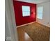 Bedroom showcasing a vibrant red accent wall, windows, neutral flooring and a stylish lamp at 4912 Atlanta St, Anderson, IN 46013
