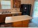 A kitchen area with natural wood cabinets, black refrigerator, island, and sliding glass doors at 4912 Atlanta St, Anderson, IN 46013