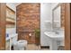 Cozy bathroom featuring exposed brick wall, pedestal sink, and modern fixtures at 501 Fletcher Ave # A, Indianapolis, IN 46203