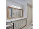 Bright bathroom featuring a double vanity, large framed mirror, and white hexagon tile flooring at 5226 W Southport Rd, Indianapolis, IN 46221