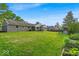Expansive backyard featuring a lush lawn, mature trees, and a play structure at 5850 E 54Th Pl, Indianapolis, IN 46226