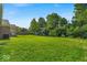 Large backyard boasting a well-manicured lawn, mature trees, and playground equipment at 5850 E 54Th Pl, Indianapolis, IN 46226