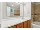 Bright bathroom featuring a white sink, wood cabinets, and tile in the shower at 5935 Oakforge Ln, Indianapolis, IN 46254