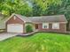 Inviting brick home with a two-car garage, neat landscaping, and a lush green lawn at 5935 Oakforge Ln, Indianapolis, IN 46254