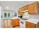 Well-lit kitchen with white appliances, wood cabinets, and a view to the backyard at 5935 Oakforge Ln, Indianapolis, IN 46254