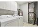 Functional laundry area with white washer and dryer, overhead cabinets, and utility appliances at 5935 Oakforge Ln, Indianapolis, IN 46254