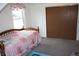 Sunlit bedroom featuring a bed with patterned bedding, a window with patterned curtains and closet space at 6052 N Deckshire Ln, Shirley, IN 47384