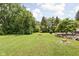Expansive backyard with mature trees featuring a fire pit and stone-lined garden, creating an inviting outdoor space at 6429 Walnut Way, Brownsburg, IN 46112