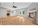 Open-concept living room with a vaulted ceiling, brick fireplace, hardwood floors, and an adjacent kitchen at 652 White Ash Trl, Mooresville, IN 46158
