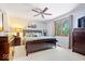 Comfortable bedroom features a ceiling fan, large bed, dresser and natural light at 7250 Royal Oakland Dr, Indianapolis, IN 46236