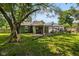 Exterior of home with covered back patio and grassy backyard under the shade of a large tree at 761 N Holmes Ave, Indianapolis, IN 46222