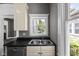 Kitchen with stainless dishwasher and double sink under a window with white cabinetry and trim at 761 N Holmes Ave, Indianapolis, IN 46222