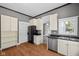 Eat-in kitchen featuring stainless dishwasher and sink, black fridge, and white cabinets, trim, and doors at 761 N Holmes Ave, Indianapolis, IN 46222