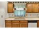 A kitchen sink with wooden cabinets, neutral counters, and a light blue curtain at 785 Cottage Ln, Greenwood, IN 46143