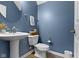 Stylish half bathroom featuring a pedestal sink, toilet, and blue walls at 9476 Oakley Dr, Indianapolis, IN 46260