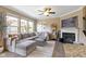 Cozy living room featuring plush sectional sofa, fireplace, large windows, and ceiling fan at 9476 Oakley Dr, Indianapolis, IN 46260