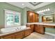 Bright bathroom with a large soaking tub next to a window with wood trim and cabinetry at 9690 Irishmans Run Ln, Zionsville, IN 46077