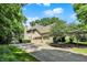 Spacious three-car garage with a long driveway and basketball hoop, surrounded by mature trees and lush greenery at 9690 Irishmans Run Ln, Zionsville, IN 46077