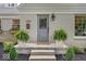 Close-up of the home's entrance, featuring a gray door, potted ferns, and stone steps at 1149 E 56Th St, Indianapolis, IN 46220