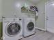 Functional laundry room with modern washer and dryer units, storage shelf, and access to exterior at 1225 Berrywood Dr, Greenwood, IN 46143