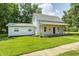 Charming two-story home with a covered porch, blue door, and green lawn at 209 Howard Ave, Arcadia, IN 46030