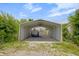 Exterior view of a metal carport in a yard with mature foliage at 2400 Walnut St, Anderson, IN 46016