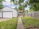 View of garage, backyard, and patio featuring green grass and a wooden fence at 3936 Graceland Ave, Indianapolis, IN 46208