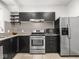 Bright kitchen features stainless steel appliances, dark cabinetry, and penny tile backsplash at 3936 Graceland Ave, Indianapolis, IN 46208