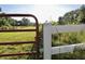 A red metal gate connected to a white wooden fence, showing a yard and tall trees beyond at 3942 Senour Rd, Indianapolis, IN 46239