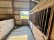A clean horse stall, next to the aisle way with an outdoor view, awaits its equine occupant at 3942 Senour Rd, Indianapolis, IN 46239