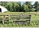 Rustic wooden and metal gate leading to the grassy field and mature trees of the property at 3942 Senour Rd, Indianapolis, IN 46239