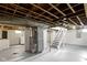 Unfinished basement featuring painted walls, cement floors, exposed duct work, and white wooden staircase at 5209 E North St, Indianapolis, IN 46219