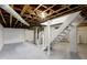 Unfinished basement features open ceiling, stairs, and painted concrete floor at 5209 E North St, Indianapolis, IN 46219