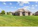 The brick home's backyard features healthy green grass and beautiful, mature trees at 5220 Orahood Ct, Plainfield, IN 46168