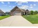 Inviting single-story home with a brick and stone facade, complemented by a two-car garage and lush, green landscaping at 5220 Orahood Ct, Plainfield, IN 46168