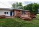 Brick house exterior with wooden deck, stairs, hot tub, door to sunroom, and green grass at 5803 Schoolwood Dr, Speedway, IN 46224