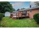 Brick house exterior with wooden deck, stairs, white shed, green grass, and a hose at 5803 Schoolwood Dr, Speedway, IN 46224