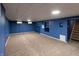 Finished basement featuring blue paneled walls, neutral carpet flooring, and built-in shelving at 5803 Schoolwood Dr, Speedway, IN 46224