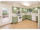 Bright eat-in kitchen with green cabinets, white appliances, tile flooring and view of the deck at 5803 Schoolwood Dr, Speedway, IN 46224