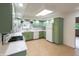Eat-in kitchen with green cabinets, white appliances, tile flooring and modern fixtures at 5803 Schoolwood Dr, Speedway, IN 46224