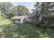 Rear view of home with light blue siding, brick facade, sunroom, overgrown lawn, and surrounded by trees at 6637 E County Road 600 S, Plainfield, IN 46168