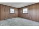 This bedroom features classic wood paneling, two windows and neutral carpet at 6637 E County Road 600 S, Plainfield, IN 46168